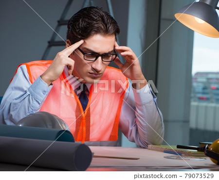 Construction architect working on drawings late at night Construction architect working on drawings late at night 79073529
