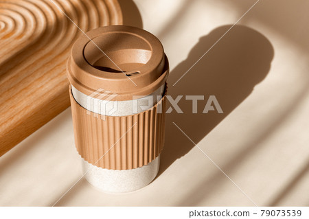 Reusable cup, biodegradable travel plastic coffee mug for take away. Sustainable bamboo eco friendly cup on natural shadow beige background. Zero waste, sustainability concept Reusable cup, biodegradable travel plastic coffee mug for take away. Sustainable bamboo eco friendly cup on natural shadow beige background. Zero waste, sustainability concept 79073539