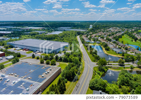 Panoramic aerial view on solar panels on absorb sunlight sustainable energy of building warehouse roof near small American town Panoramic aerial view on solar panels on absorb sunlight sustainable energy of building warehouse roof near small American town 79073589