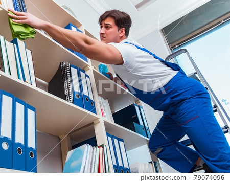Male office cleaner cleaning shelves in office 79074096