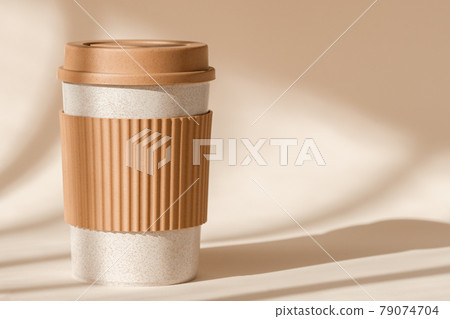 Sustainable bamboo eco friendly cup with silicone holder on natural shadow beige background. Reusable, biodegradable travel plastic coffee mug for take away. Zero waste, sustainability Sustainable bamboo eco friendly cup with silicone holder on natural shadow beige background. Reusable, biodegradable travel plastic coffee mug for take away. Zero waste, sustainability 79074704