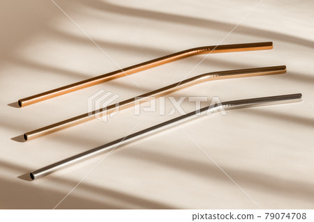 Sustainability concept. Eco friendly drinking straws from aluminium or stainless steel, reusable zero waste metal straw on neutral beige background with shadow from room windows 79074708