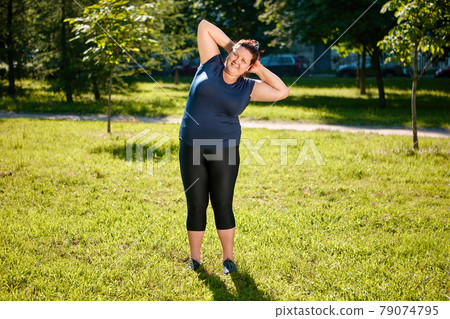 Physical training of fat femme on nature, ground acrobatics or parterre stretching. 79074795