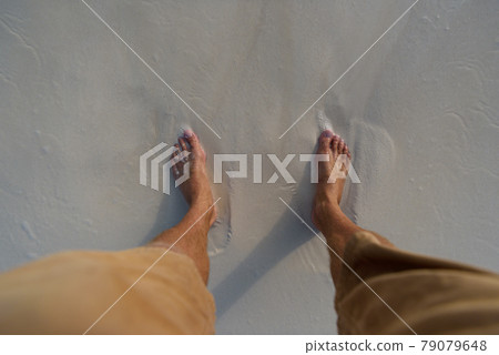 Female legs on a sandy beach with white sand and algae. 79079648