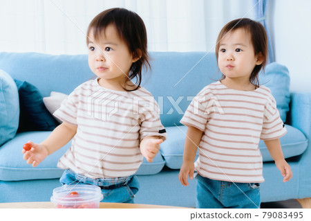 Twin girls eating petit tomatoes for snacks 79083495