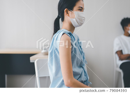 Asian woman showing plaster bandages on arm after getting vaccinated during coronavirus or covid-19 pandemic at hospital,Vaccination concept 79084393