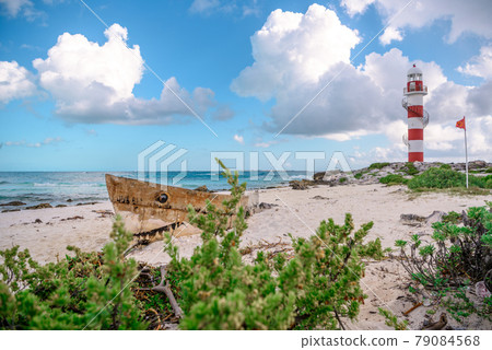 Old boat on the beach and lighthouse. Old boat on the beach and lighthouse. 79084568