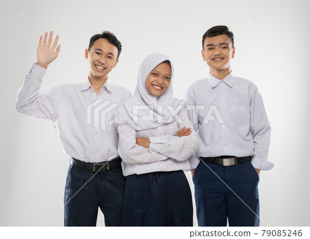 Three teenagers in junior high school uniforms smiling with say hello gesture when standing 79085246