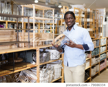Smiling African American looking for wicker basket at store 79086334