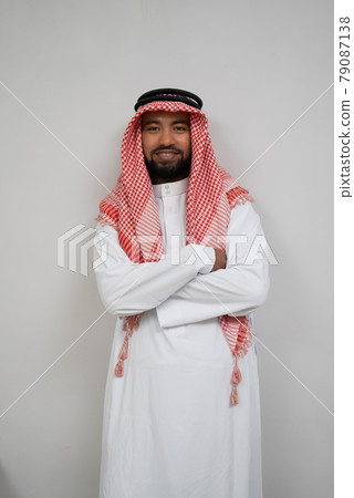 an arabian young man in a turban standing smiling with crossed hands 79087138