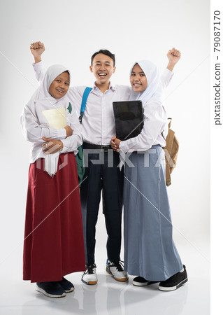 three smiling teenagers wearing school uniforms with a backpack, a book, and a laptop computer three smiling teenagers wearing school uniforms with a backpack, a book, and a laptop computer 79087170
