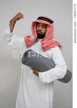 an Arab man wearing a turban feels the spirit of clenching his fist upward while carrying a mat an Arab man wearing a turban feels the spirit of clenching his fist upward while carrying a mat 79087175