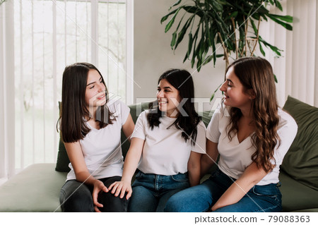 Three pretty smiling caucasian girls in white shirt sitting on the green sofa Three pretty smiling caucasian girls in white shirt sitting on the green sofa 79088363