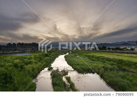天空中朦朧的光亮，流動的雲彩漂浮在溪流中，上方是遠處的山峰。 79090095