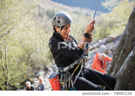 Senior woman climbing rocks outdoors in nature, active lifestyle. Senior woman climbing rocks outdoors in nature, active lifestyle. 79091228