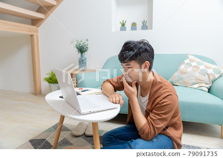 Young man working on computer at home 79091735