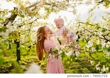 mother with baby in arms in flowering garden. surgery for child with cleft lip. mother with baby in arms in flowering garden. surgery for child with cleft lip. 79091758