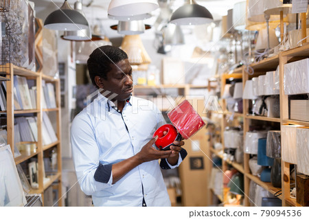 African American shopper choosing table lamp and pendant light in store African American shopper choosing table lamp and pendant light in store 79094536
