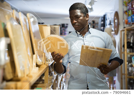 African american man choosing wooden cutting board in store 79094661