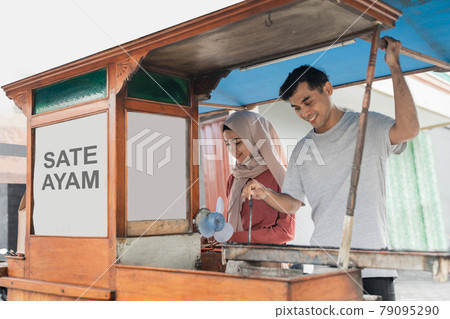 street food seller with walking stall of indonesian Chicken Satay Cooking on a Hot Charcoal Grill 79095290