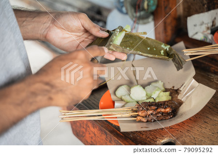 sate ayam preparation served with rice cake or lontong with peanut sauce on food paper sate ayam preparation served with rice cake or lontong with peanut sauce on food paper 79095292