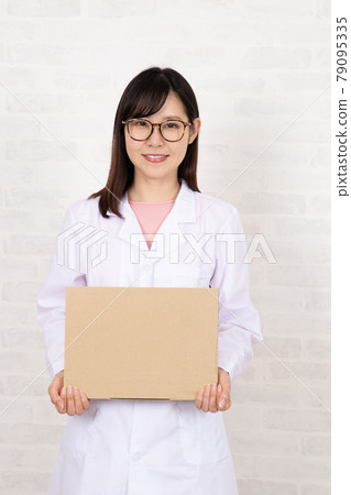 Young woman in a lab coat with glasses holding a board 79095335
