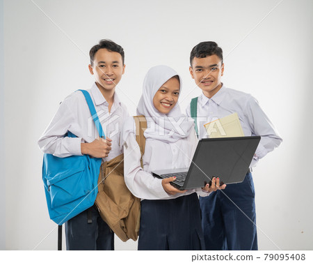 group of teenage wearing school uniforms using a laptop computer together while carrying a backpack and a book 79095408