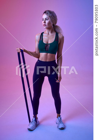 Athletic sportswoman doing exercise with rubber 79095803