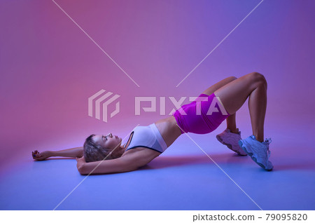 Sportswoman on workout in studio, neon background Sportswoman on workout in studio, neon background 79095820