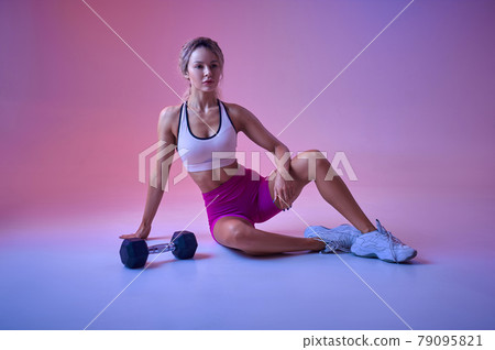 Sexy sportswoman poses with dumbbell in studio Sexy sportswoman poses with dumbbell in studio 79095821