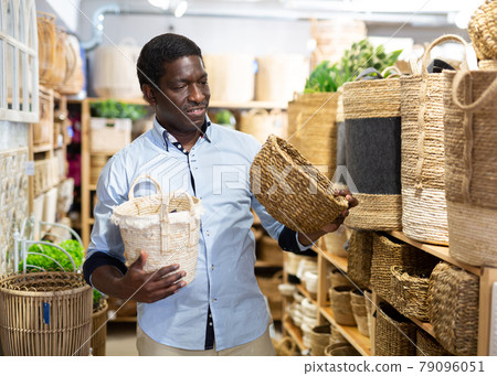 Positive african american man choosing storage wicker basket at store 79096051