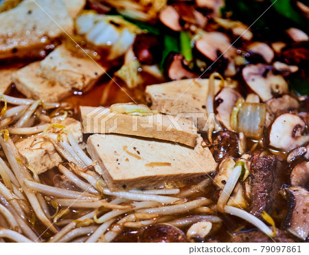 Close-up of a pot with sukiyaki, a Japanese stew with meat, with tofu, mushrooms and wheat germ in the soup Close-up of a pot with sukiyaki, a Japanese stew with meat, with tofu, mushrooms and wheat germ in the soup 79097861
