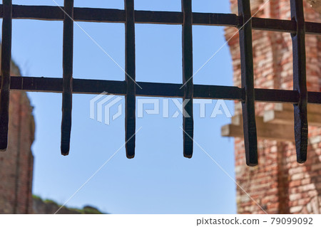 Thick metal grate covering the entrance to the fortress against the blue sky 79099092