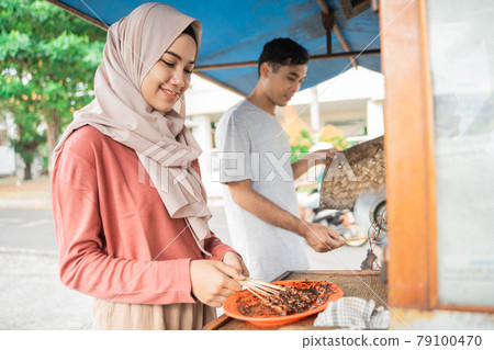 two seller preparing food on their food stall selling traditional chicken satay 79100470
