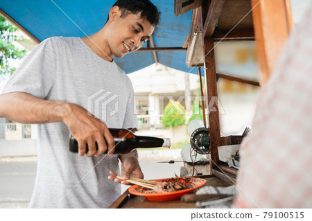 man street food seller of chicken satay with food cart selling sate ayam. 79100515