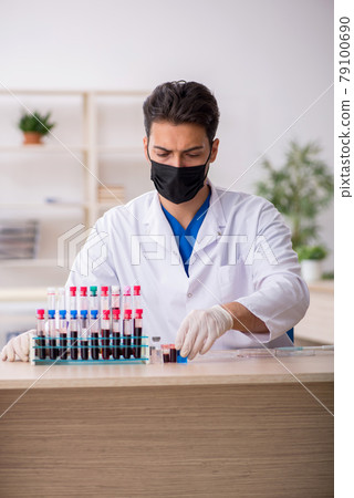 Young male biochemist testing blood samples in pandemic concept 79100690