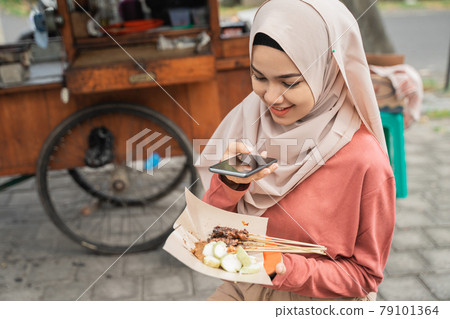 chicken satay buyer taking photo of her food using smart phone chicken satay buyer taking photo of her food using smart phone 79101364