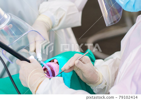 The doctor cleaning the teeth patient with ultrasonic tool 79102414