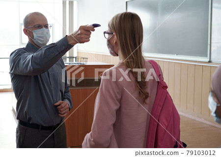 Bald mature man measuring temperature of student 79103012