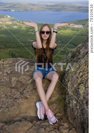 Female hiker with backpack sitting on top of the mountain enjoying the view during the day. 79103616