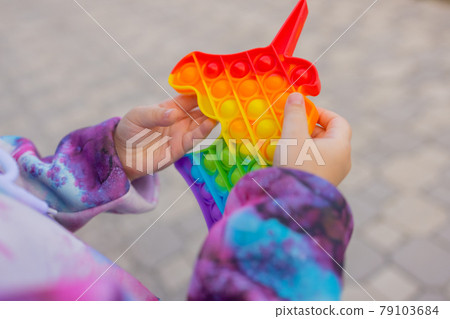 Pop it fidget toy in girl hand's. Colorful antistress kid's toy fidget. 79103684