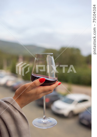 Male hand holding glass with wine on blurred natural background. Male hand holding glass with wine on blurred natural background. 79104384