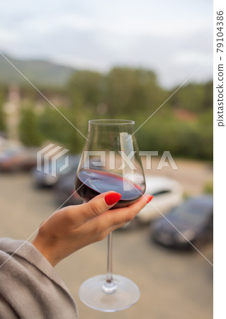Male hand holding glass with wine on blurred natural background. Male hand holding glass with wine on blurred natural background. 79104386