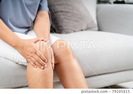 Close up of chubby woman sitting on the sofa and feeling knee pain and she massages her knee. Healthcare and medical concept. Close up of chubby woman sitting on the sofa and feeling knee pain and she massages her knee. Healthcare and medical concept. 79105815