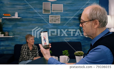 Retired male holding smartphone during online consultation Retired male holding smartphone during online consultation 79106035