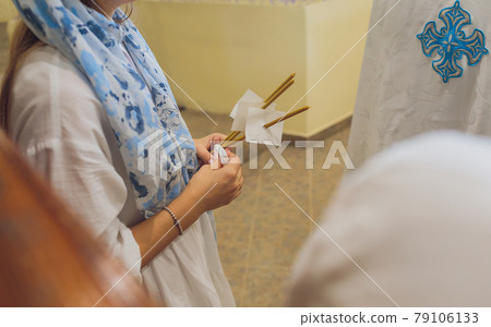 newlyweds in embroidered clothes hold lighted candle in church. wedding. close up. newlyweds in embroidered clothes hold lighted candle in church. wedding. close up. 79106133