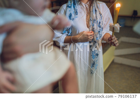 newlyweds in embroidered clothes hold lighted candle in church. wedding. close up. newlyweds in embroidered clothes hold lighted candle in church. wedding. close up. 79106137