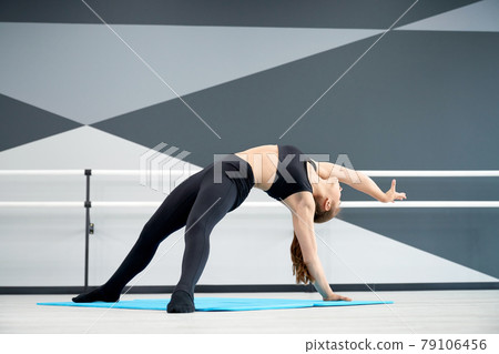 Young female dancer stretching on floor. Young female dancer stretching on floor. 79106456