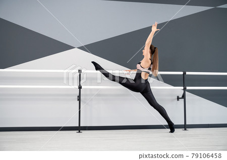 Woman stretching legs on handrails in dance studio. Woman stretching legs on handrails in dance studio. 79106458