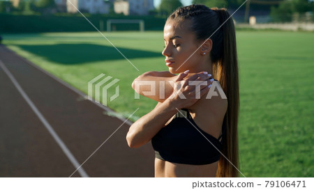 Girl warming up upper body at stadium in morning. Girl warming up upper body at stadium in morning. 79106471
